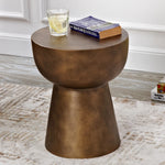 Brass end table in a living room setting with a book and drink